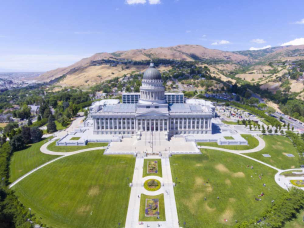 Grand building of the Utah State Capitol surrounded by mountains.